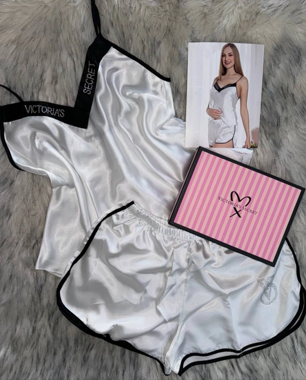 Пижамный комплект Victoria's Secret: белый топ на тонких бретелях и шорты с чёрной отделкой.